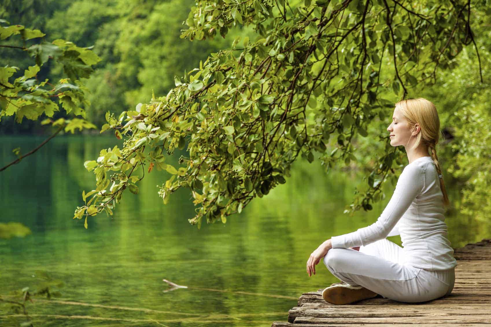 A women meditating near a river